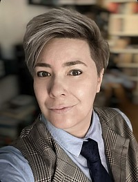 A white person with short green hair and futuristic LED glasses